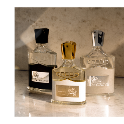 A photo shows three Creed perfume bottles, one dark liquid Aventus, one light liquid Aventus For Her, and one light liquid Aventus Cologne, with visible text including CREED, AVENUS, AVENUS FOR HER, AVENUS COLOGNE.