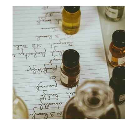 Small glass bottles containing liquids sit on a sheet of paper with handwritten notes including 3 Resorcin Citronellol Linalool Paracresol CD Phenylactique muguet Eucalyptus Phénylacétique 5 Bergamot 3 Ris Italia S/B Jakon th benzyle 24 NCE.