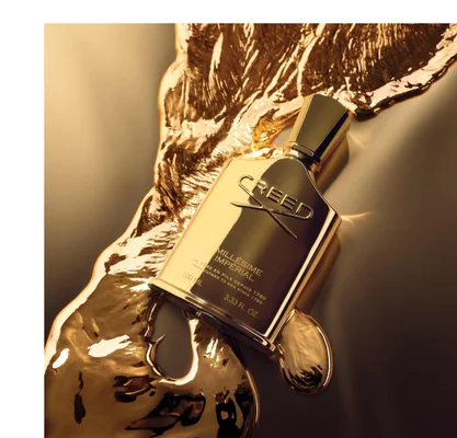 A golden Creed perfume bottle lies on a surface with molten gold, showing the text CREED MILLÉSIME IMPÉRIAL DE PERE EN FILS DEPUIS 1760 FROM FATHER TO SON SINCE 1760 100 ML 3.33 FL. OZ.