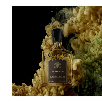 A bottle of Creed Royal Oud perfume surrounded by yellow and green swirls on a black background with the text CREED ROYAL OUD DE PÈRE EN FILS DEPUIS 1760 FROM FATHER TO SON SINCE 1760 100ML 3.33 FL. OZ.