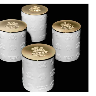 Four white ceramic containers with embossed patterns of crests, lions, and horses and gold lids featuring the text CREED 1760.
