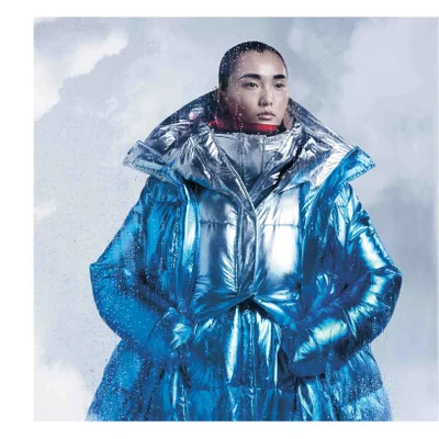 A model wears a large shiny blue puffer coat with water droplets covering the image surface.