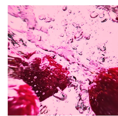 Close-up abstract view of red objects submerged in bubbly pink liquid.