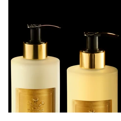 Five gold-accented Creed Aventus for Her beauty products are artfully arranged on a dark, reflective surface with golden liquid ripples, showcasing visible text that reads CREED 1760 AVENTUS FOR HER HAND CREAM CRÈME MAINS on the hand cream tube, CREED 1760 AVENTUS FOR HER SAVON LIQUIDE BODY & HAND WASH on the liquid soap bottle, CREED 1760 AVENTUS FOR HER HAND & BODY LOTION LAIT ONCTUEUX MAINS ET CORPS on the body lotion bottle, CREED 1760 on the bar of soap, and CREED AVENTUS FOR HER with a warrior on horseback graphic on the perfume bottle.