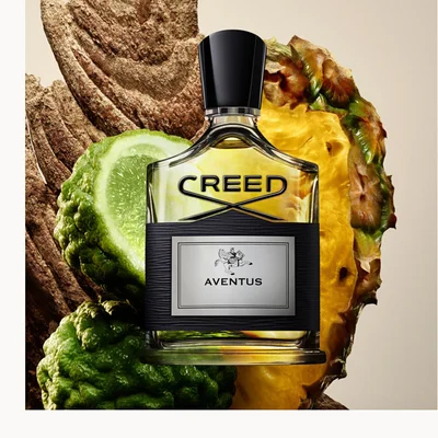 Creed Aventus bottle with pineapple, berries, vanilla, and woods arranged around it on a clean white background.